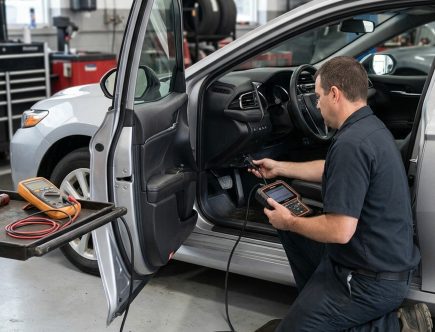 Technician connecting an OBD-II scan tool to a production sedan before ordering replacement parts