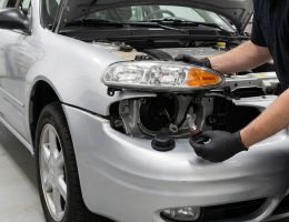 Technician servicing the 9006 low-beam headlamp assembly on a 2004 Oldsmobile Alero