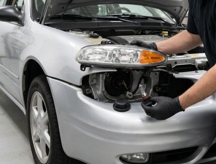 Technician servicing the 9006 low-beam headlamp assembly on a 2004 Oldsmobile Alero